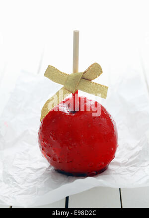 Festlicher bunte roter Glasierter Apfel mit einem Bogen bedeckt in zuckerhaltigen Bonbons Sirup für eine Feier Urlaub Stockfoto