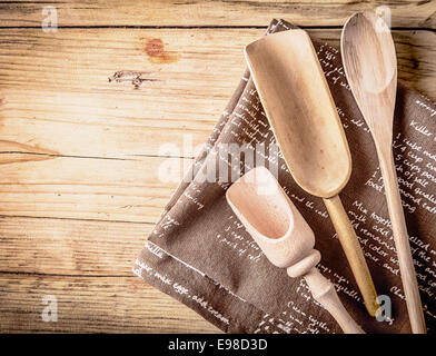 Rustikale Kochutensilien mit einem Holzlöffel und zwei handgeschnitzt rustikale Kugeln auf ein zusammengefaltetes Blatt des Hessischen auf einem hölzernen Zähler nach oben in eine ländliche Küche liegend Stockfoto