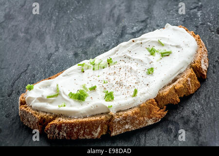 Gesunder fettarmer Sahne Käse und Schnittlauch auf einer Scheibe frisch gebackenes Roggenbrot, Nahaufnahme niedrigen Winkel Stockfoto