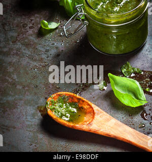 Herstellung von köstlich frisches Pesto-Sauce mit frisch gemahlener Basilikum Blätter, Parmesan-Käse und Pinienkernen mit Olivenöl vermischt und in einem Holzlöffel auf einen Schiefer Zähler angezeigt Stockfoto