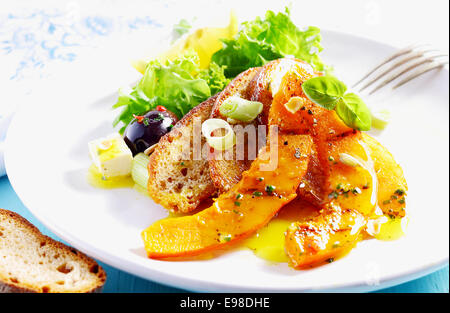 Mediterraner Salat mit Salat, Mozzarella-Käse-Würfel, Scheiben Brot sehr lecker und frisch, Basilikumblätter, Oliven und gewürzt mit Olivenöl auf einem weißen Teller Stockfoto