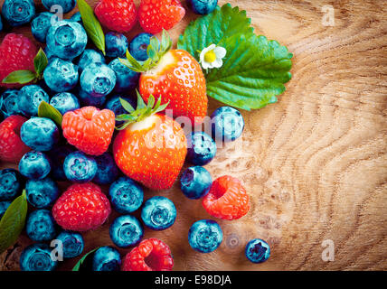 Draufsicht der gemischten Reifen Herbst Beeren wie Erdbeeren, Himbeeren und Heidelbeeren auf einer dekorativen Woodgrain-Oberfläche Stockfoto