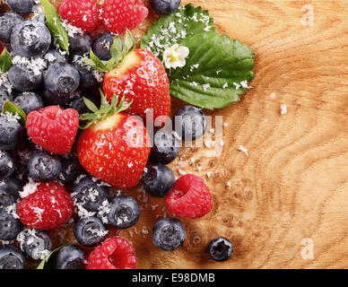 Ansicht von oben aus einer Zusammenstellung von Beeren wie Heidelbeeren, Himbeeren und Erdbeeren über einen Holztisch mit Textfreiraum Stockfoto