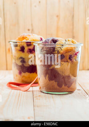 Zwei Gläser mit leckeren Vanille und Schokolade Hausgemachte Früchtekuchen, auf einem Holztisch in Nahaufnahme Stockfoto