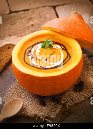 Köstliche Kürbis oder Butternut Suppe, serviert in den ausgehöhlten Kürbis beträufelt mit Sahne und Soße für eine herzhafte Mahlzeit im Herbst Stockfoto