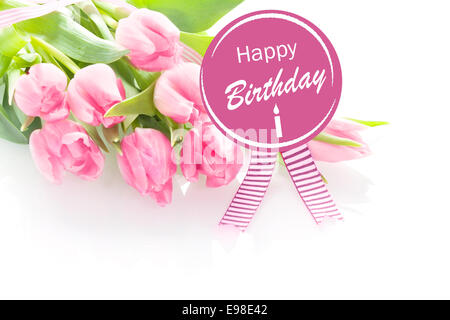 Reihe von schönen frischen rosa Tulpen mit einem Happy Birthday Ansage auf eine Runde violette Rosette mit festlichen Bändern über Stockfoto