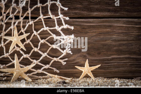 Nautische Hintergrund mit Seestern und Diamant-Muster Fischernetz auf Holzbrettern mit einem unverwechselbaren Woodgrain-Muster über frischen Strandsand mit Exemplar Stockfoto