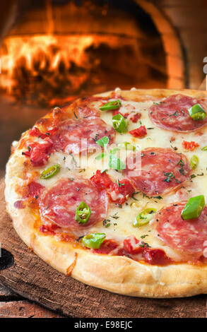 Frisch gebackene traditionelle italienische Salami oder Salami Pizza auf eine knackige goldenen Tortekruste Kaminfeuer in einem Restaurant oder Pizzeria Pizza Ofen Stockfoto