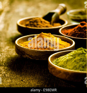 Schüssel mit asiatischen Curry-Pulver gemischt aus einer Mischung von Gewürzen mit Kurkuma und Masala, selektiven Fokus auf ein Grunge-rustikal aus Holz Stockfoto