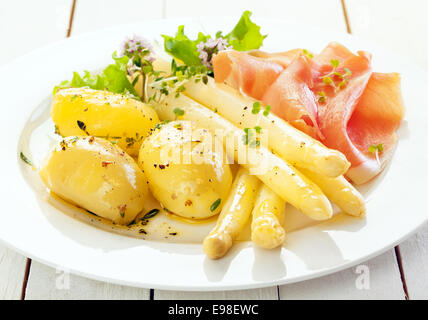 Kalter Spargel mit Parmaschinken und gekochtem Babykartoffeln serviert mit Salat und gehackte frische Kräuter, Nahaufnahme auf einer Platte Stockfoto
