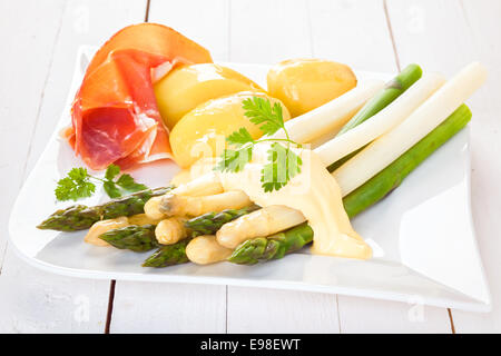 Gekocht kalt weißen und grünen Spargel mit Schinken und gekochte Kartoffeln mit Mayonnaise und frischem Koriander auf einem modernen weißen Teller serviert Baby, Nahaufnahme Stockfoto