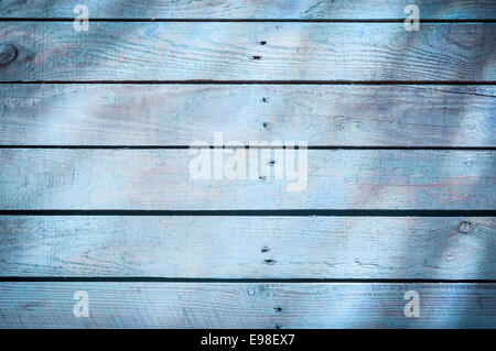 Hintergrund-Textur des verblichenen blauen Holzbretter mit einem Woodgrain-Muster, eine zentrale Reihe von Nägeln und Sonnenschein und Schatten Wirkung Stockfoto