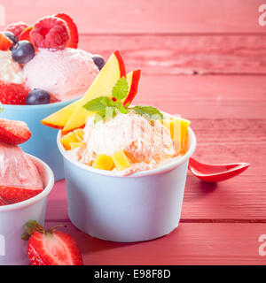 Einzelne Portionen kühles erfrischendes Eis garniert mit frischen tropischen Früchten wie Apfel, Erdbeeren, Heidelbeeren und Himbeeren, quadratisches Format mit Exemplar Stockfoto