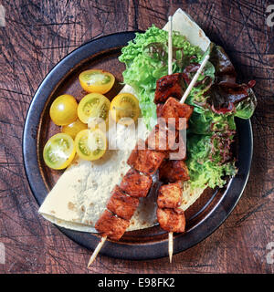 Gegrilltes Schweinefleisch-Spieße mit frischen Tomaten und Salat Salat serviert auf einem Mais-Tortilla, Draufsicht auf einen alten rustikalen erzielte Holzoberfläche Stockfoto