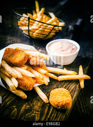 Knusprig goldene frittiertem Fisch und Kartoffel-Chips oder Pommes frites serviert mit einer pikanten Mayonnaise Dip auf einem alten Holztisch in ein Fischgeschäft Stockfoto