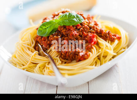 Schale mit leckeren italienischen Spaghetti Bolognese mit einem reichhaltigen Fleisch und Tomatensauce belegt und garniert mit geriebenem Parmesankäse mit einem Keil hinter Stockfoto