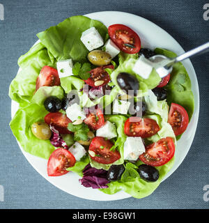 Teller mit gesunder mediterraner Salat mit Feta-Käse, schwarzen und grünen Oliven, Tomaten und Kopfsalat, Nahaufnahme Draufsicht im quadratischen format Stockfoto