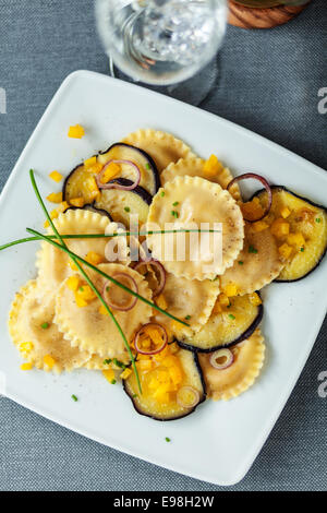 Draufsicht auf einen Teller mit runden Italienisch Girasole Ravioli Pasta mit Auberginen, Zwiebeln und Käse für ein gutes herzhaftes vegetarisches Gericht Stockfoto