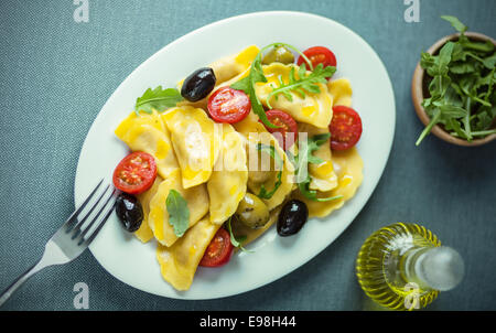 Italienische Ravioli-Salat mit Rucola oder Rucola, Cherry-Tomaten und Oliven beträufelt mit Olivenöl, Ansicht von oben Stockfoto