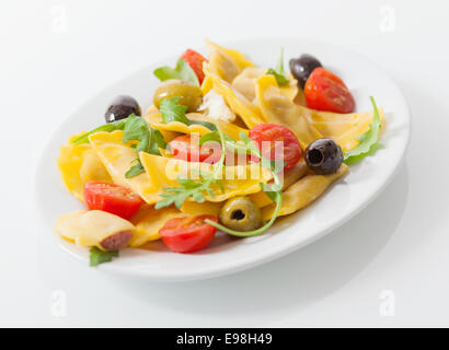 Leckere herzhafte italienische Ravioli-Salat mit gefüllte Ravioli Pasta, frischen Rock und Cherry-Tomaten und eine Vielzahl von Oliven, Nahaufnahme niedrigen Winkel auf einem Teller Stockfoto