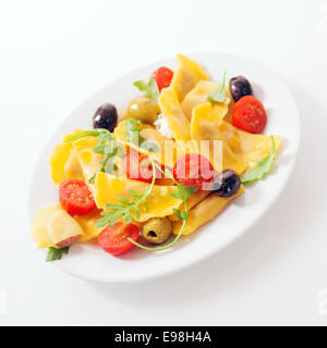 Farbenfrohe italienische Ravioli-Salat mit Rucola oder Rucola, frisch halbierte Kirschtomaten und eine Vielzahl von Oliven beträufelt mit Olivenöl Stockfoto