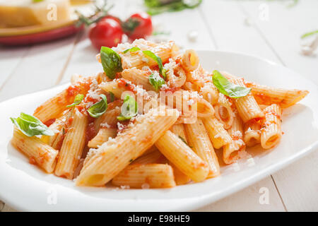 Ausschank von würzig herzhafte italienische Penne-Nudeln mit frischem Basilikum garniert und garniert mit geriebenem Parmigiano-Reggiano oder Parmesan, Stockfoto