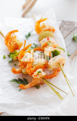 Garnelen oder Shrimps Kebab Vorspeise mit gegrilltem rosa Garnelen am Spieß mit Zitrone und frischen Kräutern für einen leckeren Start in eine Mahlzeit Stockfoto