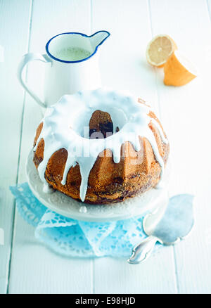 Frisch gebackene verglaste Zitrone ring Kuchen serviert auf einer Etagere zum Nachtisch einen Krug spritzige citrus Sauce mit einem Spatel zu dienen, erhöhte Ansicht Stockfoto