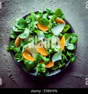 Valanenaella Locusta Salat, dunkel grünen Blattsalat Pflanzen auch bekannte lokal in Frankreich als Pappmaché oder Feldsalat mit Mandarinen und Scheiben Parmesankäse, Overhead anzeigen in eine Schüssel geben Stockfoto