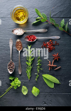 Nahrungsmittelelementen und Löffel auf schwarzer Holztisch Stockfoto