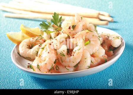 Gegrillte rosa geschälte marine Garnelen gewürzt mit Olivenöl und Kräutern serviert mit Zitrone und Brot sticks für leckere Meeresfrüchte Vorspeise bis zum Abendessen, auf blau-türkis Stockfoto