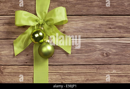 Dekorative grüne Bogen dekoriert mit zwei Weihnachtskugel Ornamente auf einem hölzernen Hintergrund mit Exemplar für Ihre saisonalen Gruß Stockfoto