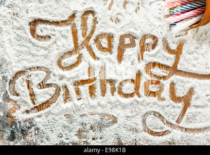 Mehl Artwork mit Essen und Handabdrücke, Spaß Hintergrund mit den Worten HAPPY BIRTHDAY und menschlichen Handpints in verstreuten Mehl auf einer hölzernen Tischplatte. Stockfoto