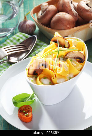 Bootsform Gericht der Pilz Tagliatelle mit eine Schale mit frischen Champignons im Hintergrund. Stockfoto