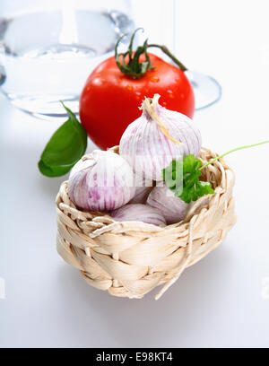 Ein Korb mit Tomaten, Knoblauch und Petersilie auf weißem Hintergrund für italienische Begriffe Stockfoto