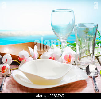 Stilvolle Gedeck mit Orchideen und schöne moderne Geschirr in einem exotischen Restaurant am Strand Stockfoto