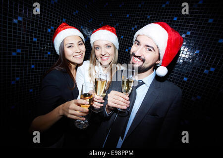 Gruppe von fröhlichen Geschäftsleute in Santa Kappen Toasten mit Champagner in Nachtclub Stockfoto