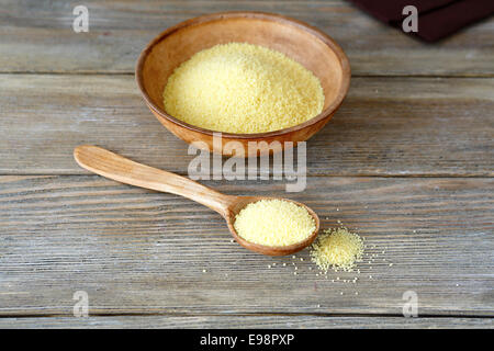 Couscous in einer Ton-Schüssel und Löffel aus Holz, Lebensmittelzutat Stockfoto