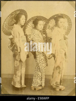 Das Foto zeigt drei Frauen mit traditionellen Regenschirmen, die in Japan spazieren gehen. Das Bild zeigt Aspekte der japanischen Kultur, einschließlich der Verwendung von Regenschirmen als Teil des täglichen Lebens und der Mode während des frühen 20. Jahrhunderts. Stockfoto