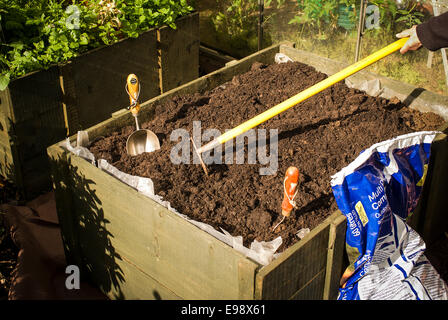 Hohen hölzernen Pflanzer mit Kompost vorbereitet und geharkt vor dem Einpflanzen Stockfoto