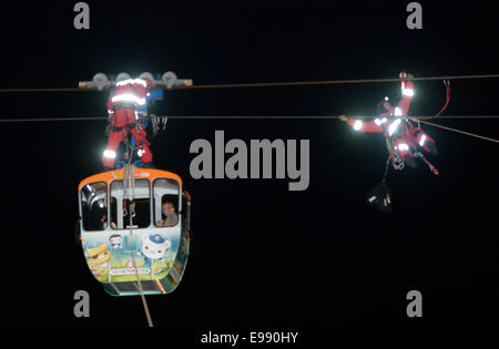 Köln, Deutschland. 21. Oktober 2014. Arbeiter Abseilen eine vierköpfige Familie aus eine Seilbahn über den Rhein in Köln, 21. Oktober 2014 gefangen zu retten. Wegen zu starken Windes war die Seilbahn zwischen zwei Säulen über dem Rhein stecken und die Familie gerettet werden mussten. Bildnachweis: Dpa picture Alliance/Alamy Live News Stockfoto