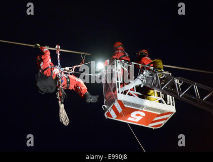 Köln, Deutschland. 21. Oktober 2014. Arbeiter Abseilen eine vierköpfige Familie aus eine Seilbahn über den Rhein in Köln, 21. Oktober 2014 gefangen zu retten. Wegen zu starken Windes war die Seilbahn zwischen zwei Säulen über dem Rhein stecken und die Familie gerettet werden mussten. Bildnachweis: Dpa picture Alliance/Alamy Live News Stockfoto