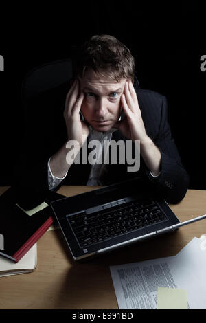 Vertikales Bild eines müden Geschäftsmannes arbeiten bis spät in die Nacht mit schwarzem Hintergrund Stockfoto