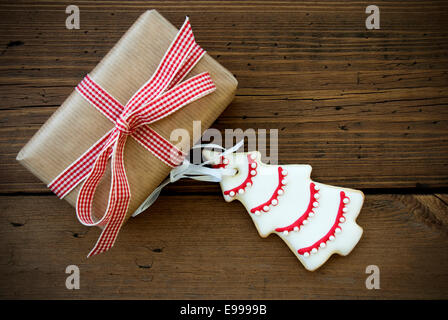 Geschenk mit Schleife und Weihnachtsbaum Cookie auf hölzernen Hintergrund mit Textfreiraum Stockfoto