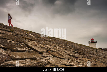 Eine Frau sieht-Schilder mit Burry Port Leuchtturm im Hintergrund. Lllanelli, Carmarthenshire, West Wales. VEREINIGTES KÖNIGREICH. Stockfoto