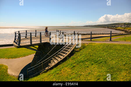 Ein Frau Radfahrer blickt in Richtung Burry Port von einer Aussichtsplattform auf dem Millennium Küstenpfad, Wales. Stockfoto