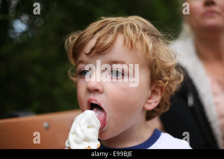 kleiner Junge essen Eis mit Mama im Hintergrund Stockfoto