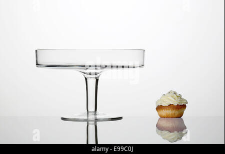 Hohe Schlüssel Foto von einem Glas Kuchen stehen mit einem Cupcake und deren Reflexionen unter ihnen. Stockfoto
