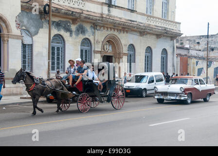 Ein Pferd Pferdekutsche gefolgt von einem Oldtimer Ford Fairlane escort Touristen auf dem berühmten Malecon in Havanna Kuba. Stockfoto