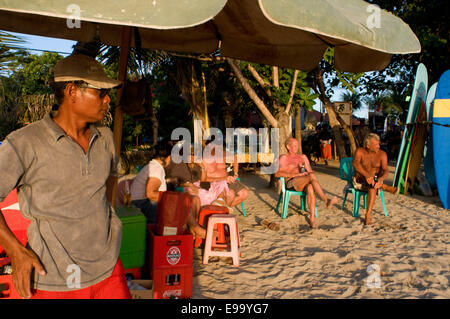 Strand von Kuta bei Sonnenuntergang. Bier trinken. Bali. Kuta ist eine Küstenstadt im Süden von der Insel Lombok in Indonesien. Die scen Stockfoto